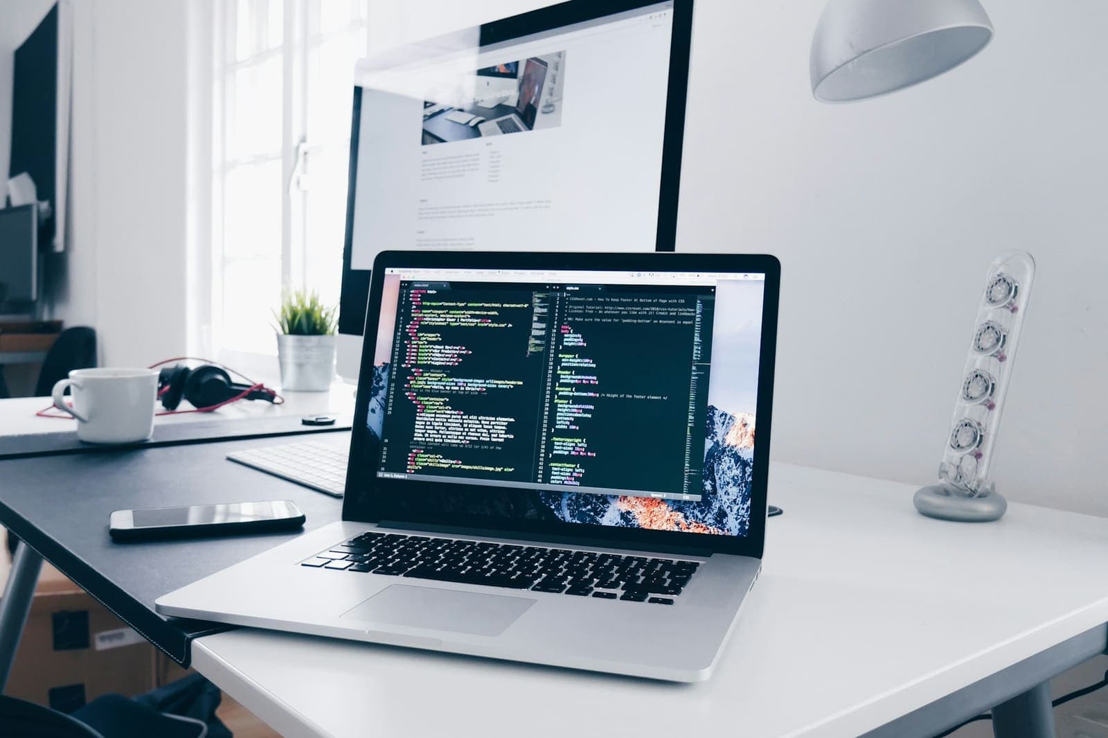 Laptop showing source code on a bright, minimal developer desk